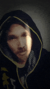 a man wearing a black and yellow hoodie with the letter x on the front