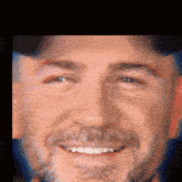 a man with a beard is smiling and wearing a baseball cap