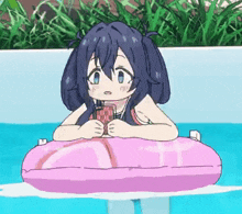 a girl is sitting on a pink life preserver in a pool .
