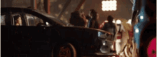 a group of people are standing around a car in a parking lot .