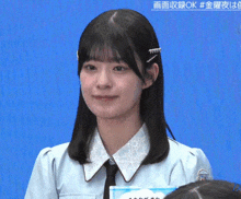 a girl in a blue shirt and tie is smiling in front of a blue background