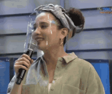 a woman wearing a face shield is holding a microphone and smiling ..
