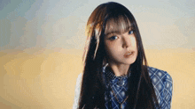 a woman with long hair and blue eyes is wearing a plaid shirt and necklace .