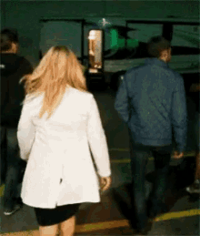 a woman in a white coat is walking with a man