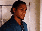 a man with dreadlocks is wearing a blue jacket and a black shirt
