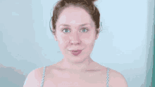 a woman without makeup is smiling and making a funny face with her hands .