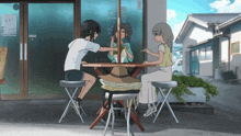 three girls are sitting at a table in front of a building with chinese writing on the window