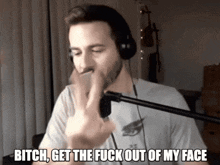a man wearing headphones and a white shirt says " bitch get the fuck out of my face "
