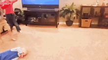 a baby is laying on the floor in a living room while a woman is dancing in front of a television .