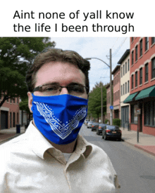 a man wearing a blue bandana on his face with a caption that says ain 't none of yall know the life