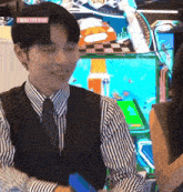 a man in a suit and tie is smiling in front of an arcade machine