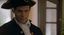 a man wearing a pirate hat looks at the camera with a slight smile on his face