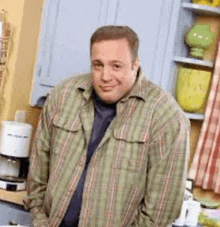 a man in a plaid shirt is smiling in a kitchen