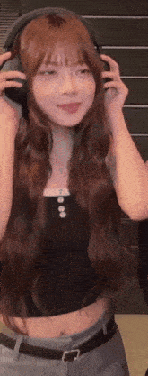 a woman with long hair wearing headphones and a black tank top