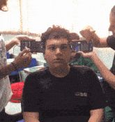 a boy wearing a black shirt that says ' col est ' on it is being photographed