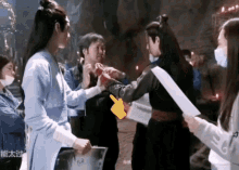a group of people are standing around a man holding a piece of paper with the number 6 on it