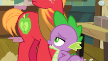 a red pony with an apple on its back is standing next to a purple dragon with green spikes