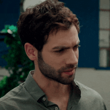 a close up of a man 's face with a beard and a green shirt