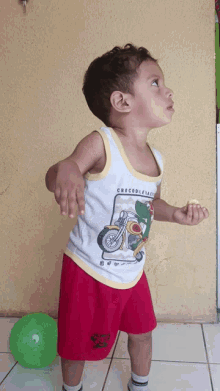 a young boy wearing a white tank top that says crocodile