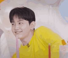 a young man in a yellow shirt is smiling and holding a pink candle
