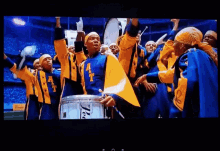 a group of marching band members wearing blue and yellow uniforms with the letter t on the front