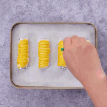a person is holding a tray with four pieces of food on it .