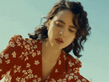 a woman in a red and white floral dress looks down