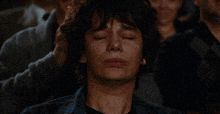 a man with his eyes closed is crying in front of a crowd