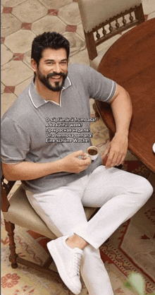 a man with a beard is sitting at a table with a cup of coffee