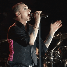 a man with a tattoo on his arm sings into a microphone on stage