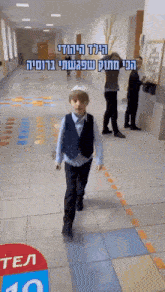 a young boy is walking down a hallway with hebrew writing on it