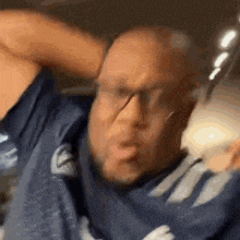 a man wearing glasses and a blue shirt is making a funny face while holding a bottle of milk .