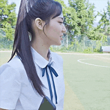 a girl in a school uniform with a ponytail is standing in a field