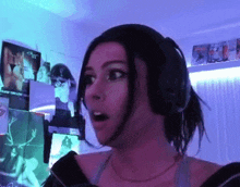 a woman wearing headphones is standing in front of a wall with posters on it .