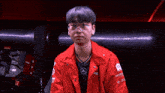 a young man wearing glasses and a red jacket with a mercedes logo on it