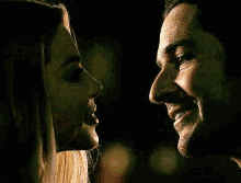 a man and a woman are looking at each other in a dark room .