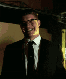 a man in a suit and tie is smiling in the dark