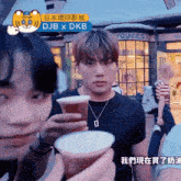 a man holding a cup in front of a store called dukes