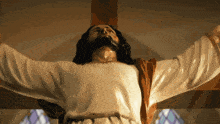 a statue of jesus with his arms outstretched in front of a stained glass window