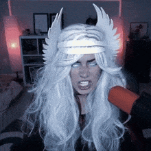 a woman with long white hair and wings on her head is screaming into a microphone