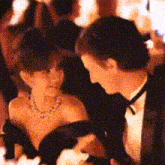 a man in a tuxedo holds a woman in a black dress