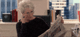 a woman wearing glasses is reading the new york times newspaper