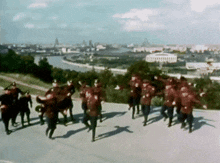 a group of soldiers are marching down a street with a city in the background