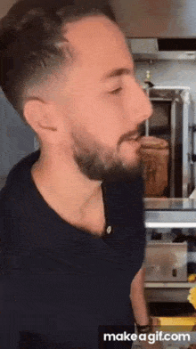 a man with a beard is standing in front of a grill and eating food .