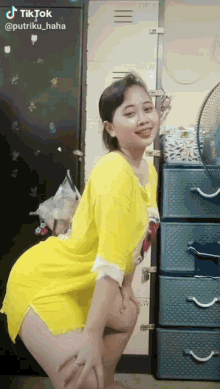 a woman in a yellow dress is kneeling in front of a fan