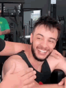 a man with a beard is smiling in a gym while being hugged by a woman .