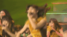 a group of women are dancing and one of them is wearing a yellow dress