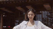 a woman in a white sweater is standing in front of a building .