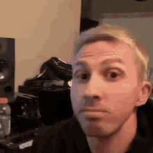 a man with blonde hair is making a funny face in front of a speaker .