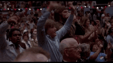 a crowd of people in a stadium with their arms in the air